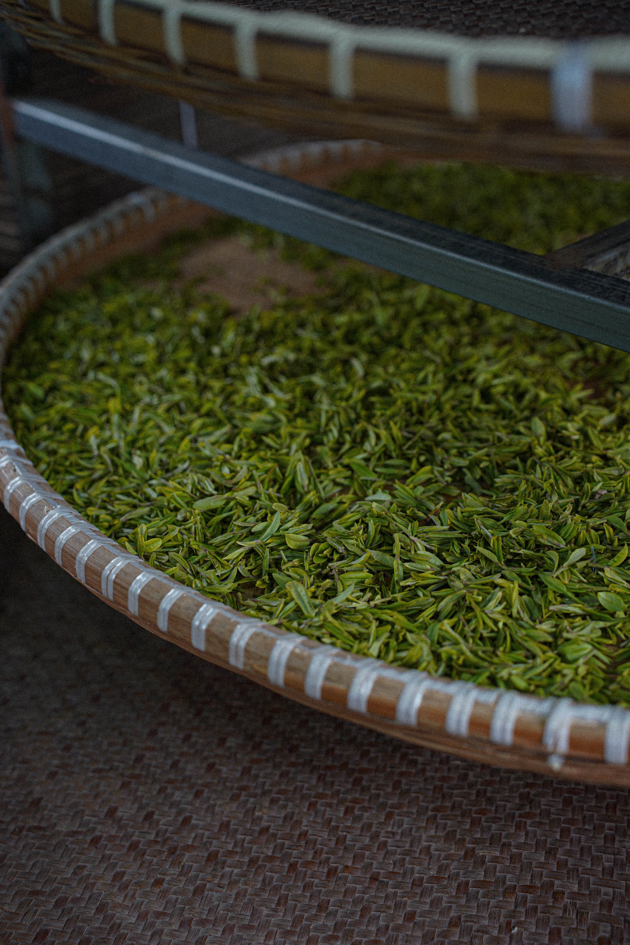 Close-up of a woven basket with green tea leaves.