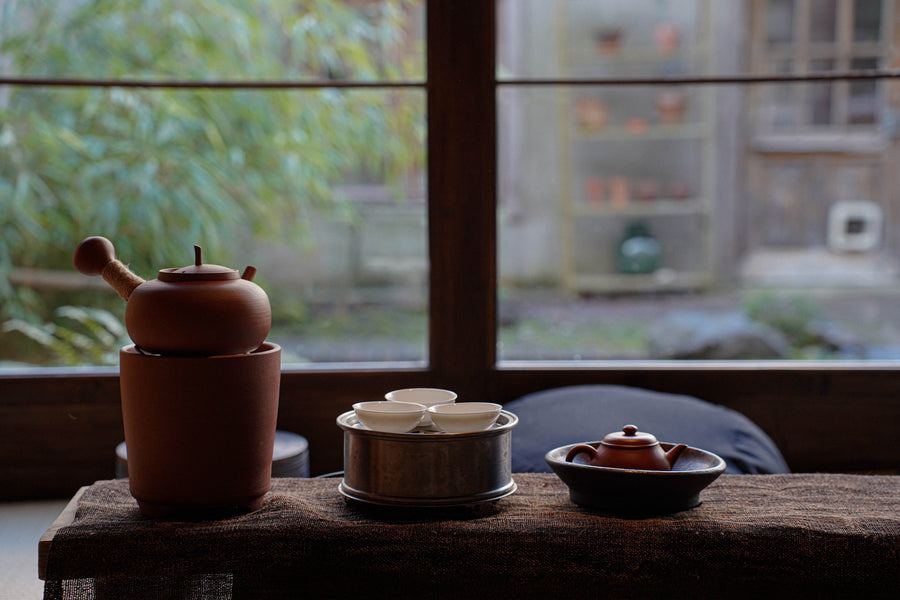 YIN CHA Tea ceremony set on a wooden table with a window view in the background