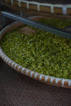 Close-up of a woven basket with green tea leaves.