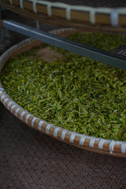 Close-up of a woven basket with green tea leaves.