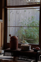 Tea set on a table with a window in the background showing greenery